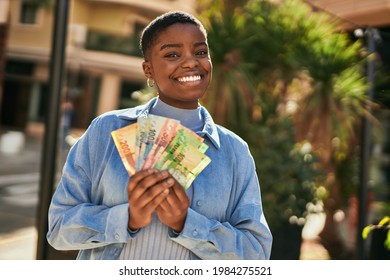 Young African American Woman Smiling Happy Holding South Africa Rand Banknotes At The City.