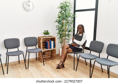 Young african american woman smiling happy holding binder at waiting room.