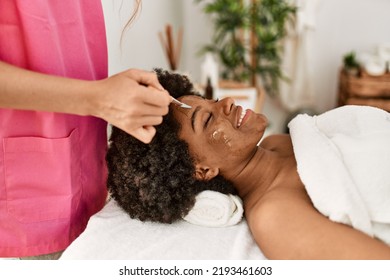 Young African American Woman Smiling Confident Having Facial Treatment At Beauty Center