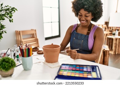 Young african american woman smiling confident painting clay pot at art studio - Powered by Shutterstock