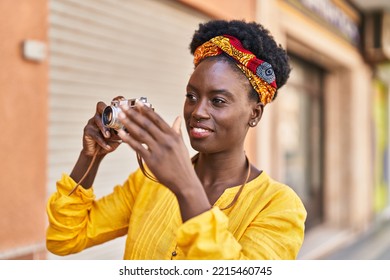 Young African American Woman Smiling Confident Using Vintage Camera At Street