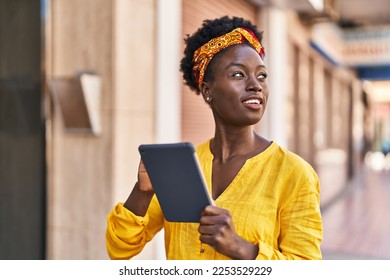 Young african american woman smiling confident using touchpad at street - Powered by Shutterstock