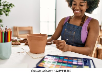 Young african american woman smiling confident painting clay pot at art studio - Powered by Shutterstock