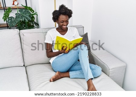 Young african american woman smiling confident reading book at home