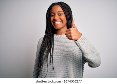 Young african american woman standing casual and cool over grey isolated background doing happy thumbs up gesture with hand. Approving expression looking at the camera showing success.