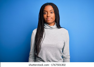 Young african american woman standing wearing casual turtleneck over blue isolated background Relaxed with serious expression on face. Simple and natural looking at the camera.