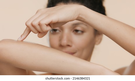 Young African American Woman Strokes Her Smooth Forearm On Beige Background | Smooth Skin Concept