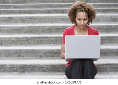 Young African American Woman Using Laptop On Steps Outdoors