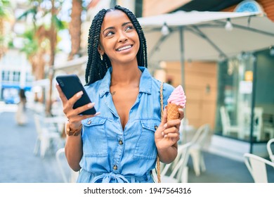 Young African American Woman Using Smartphone And Eating Ice Cream At The City.