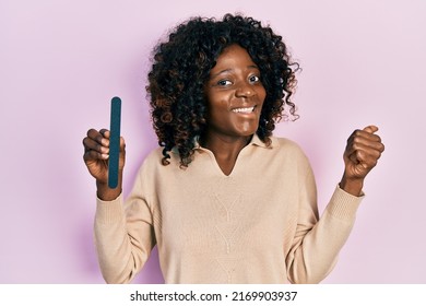 Young African American Woman Using File Nail Pointing Thumb Up To The Side Smiling Happy With Open Mouth 