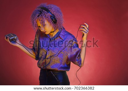 young african american woman with vintage clothes listening to music with her walkman
