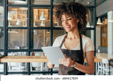 Young african american woman waitress taking orders from clients in cafe