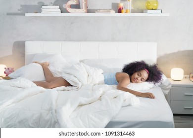 Junge Afroamerikanerin, die zu Hause aufwacht. Portrait von glücklichem schwarzen Mädchen lächeln, genießen Sie eine große King-Size Matratze für sich.