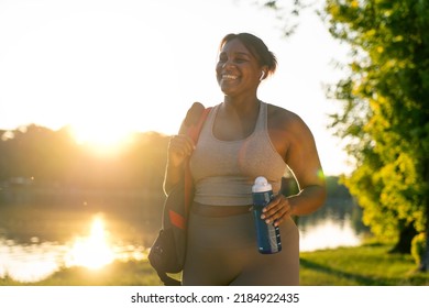 Young African American Woman Walking With Bag And Bottle Of Water Through The Park In A Summer Day