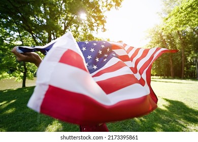 Young African american woman is waving American flag on top of at nature background. USA resident, US citizen. Immigration concept                               