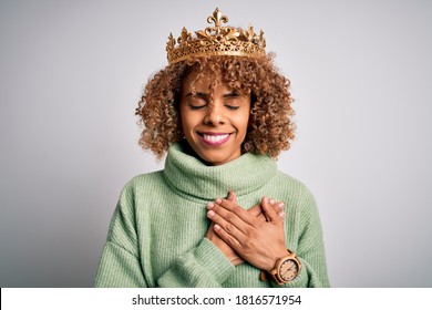 Young African American Woman Wearing Golden Crown Of Queen Over Isolated White Background Smiling With Hands On Chest With Closed Eyes And Grateful Gesture On Face. Health Concept.