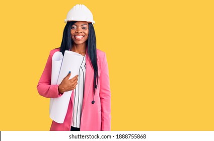 Young african american woman wearing architect hardhat holding blueprints looking positive and happy standing and smiling with a confident smile showing teeth  - Powered by Shutterstock