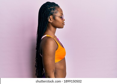 Young African American Woman Wearing Bikini And Sunglasses Looking To Side, Relax Profile Pose With Natural Face With Confident Smile. 