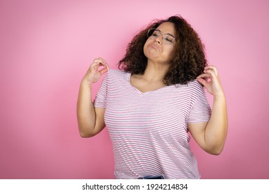 Young African American Woman Wearing Red Stripes T-shirt Over Pink Background Holding Her T-shirt With A Successful Expression