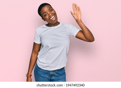 Young African American Woman Wearing Casual White T Shirt Waiving Saying Hello Happy And Smiling, Friendly Welcome Gesture 
