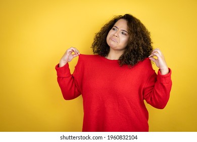 Young African American Woman Wearing Red Sweater Over Yellow Background Holding Her T-shirt With A Successful Expression