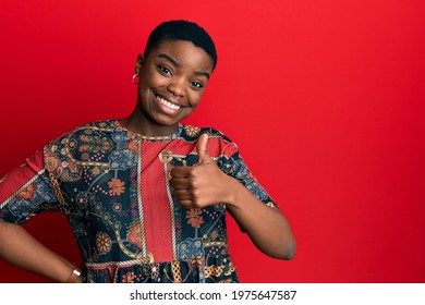 Young african american woman wearing african style doing happy thumbs up gesture with hand. approving expression looking at the camera showing success. 