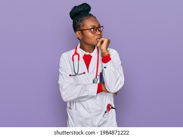 Young African American Woman Wearing Doctor Uniform And Stethoscope With Hand On Chin Thinking About Question, Pensive Expression. Smiling With Thoughtful Face. Doubt Concept. 