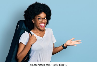 Young african american woman wearing guitar case celebrating achievement with happy smile and winner expression with raised hand
