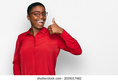 Young african american woman wearing casual clothes and glasses smiling happy and positive, thumb up doing excellent and approval sign 