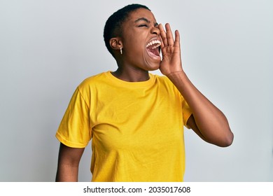 Young african american woman wearing casual yellow t shirt shouting and screaming loud to side with hand on mouth. communication concept. 