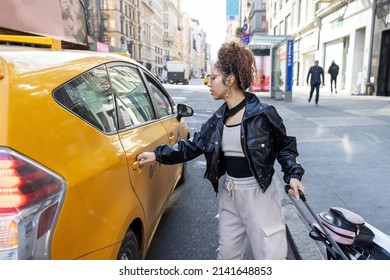Young African American woman wearing black leather jacket in yellow taxi cab