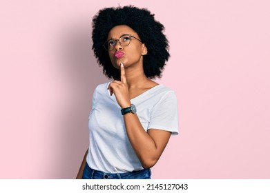Young african american woman wearing casual white t shirt thinking concentrated about doubt with finger on chin and looking up wondering 