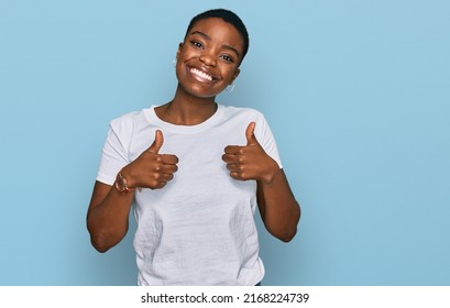 Young african american woman wearing casual white t shirt success sign doing positive gesture with hand, thumbs up smiling and happy. cheerful expression and winner gesture.  - Powered by Shutterstock
