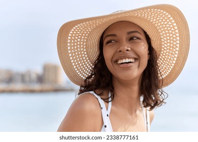 Young african american woman wearing summer hat looking to the side at seaside - Shutterstock ID 2338777161