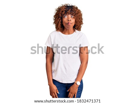 Young african american woman wearing casual white tshirt making fish face with lips, crazy and comical gesture. funny expression. 