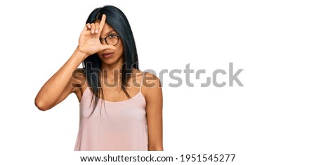 Young african american woman wearing casual clothes and glasses making fun of people with fingers on forehead doing loser gesture mocking and insulting. 