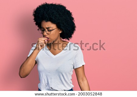 Young african american woman wearing casual white t shirt feeling unwell and coughing as symptom for cold or bronchitis. health care concept. 
