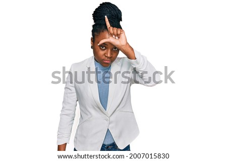 Young african american woman wearing business clothes making fun of people with fingers on forehead doing loser gesture mocking and insulting. 