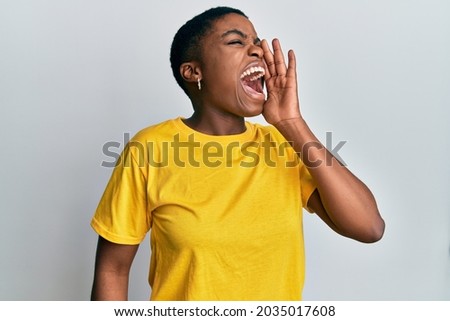 Young african american woman wearing casual yellow t shirt shouting and screaming loud to side with hand on mouth. communication concept.  ストックフォト © 