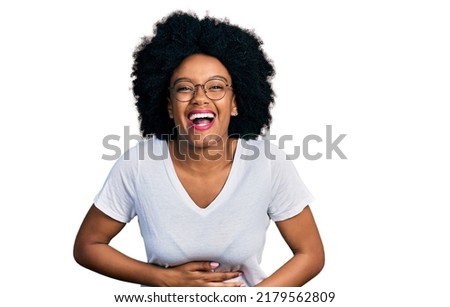 Young african american woman wearing casual white t shirt smiling and laughing hard out loud because funny crazy joke with hands on body. 