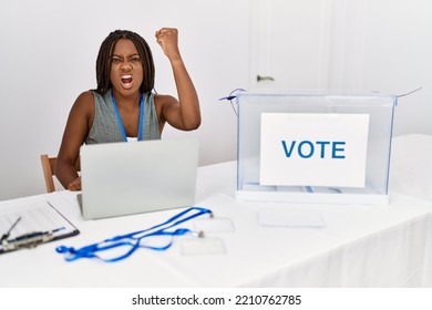 Young african american woman working at political election sitting by ballot angry and mad raising fist frustrated and furious while shouting with anger. rage and aggressive concept.  - Shutterstock ID 2210762785