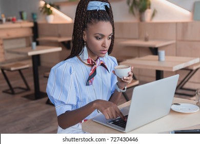 Young African American Woman Working With Laptop And Drinking Coffee At Cafe