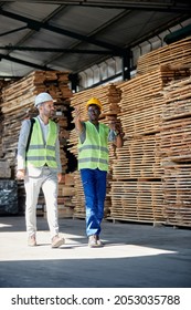 Young African American Worker Communicating With Inspector While Conducting Him Through Lumber Warehouse. Copy Space.