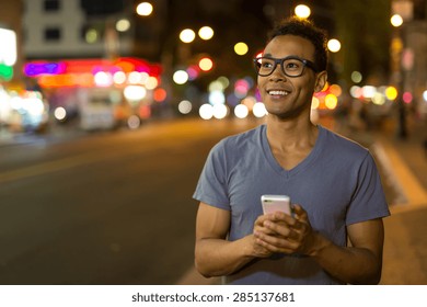 Young African Asian Man In New York City Texting Cell Phone At Night