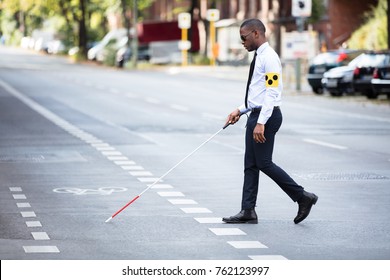 Young African Blind Man Wearing Armband Walking With Stick Crossing Road