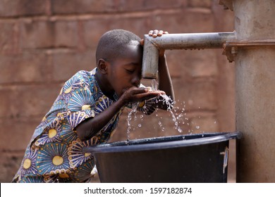 Young African Boy Drinking Water From The Community Borehole Hand Pump