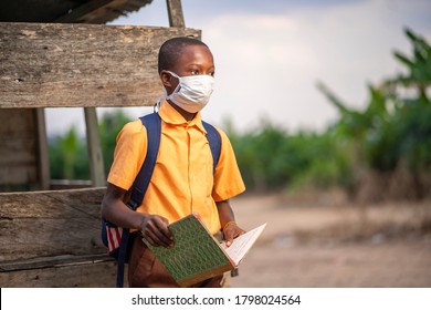 young African boy in uniform, with back pack and  opened book-Black guy with face mask-out door school concept