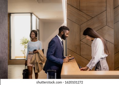 Young African businessman in formalwear bending over reception counter in hotel lounge while talking to receptionist - Powered by Shutterstock - Get 15% off with code: PIKWIZARD15