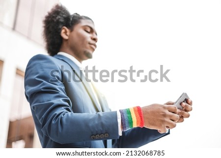 young african businessman with LGBT bracelet using smartphone outdoors. Diversity concept.
