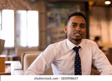 Young African businessman sitting and smiling in coffee shop